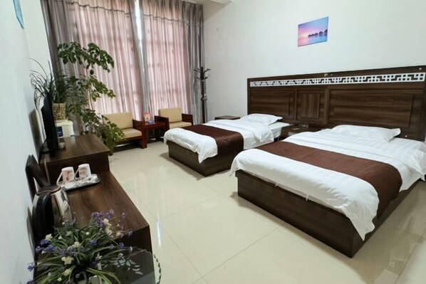 A hotel room with two beds, a desk, a chair, a plant, and a window with curtains. - Suyun Express Hotel (Luoping)