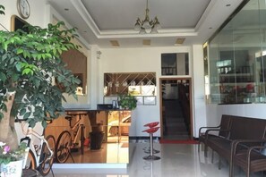A spacious living area with a dining table, a bicycle, a potted plant, and a staircase leading to an upper level. - Suyun Express Hotel (Luoping)