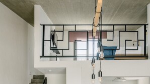 A modern interior with a staircase, a loft bedroom, and a dining area. - Irissa Suites (Nafplio)