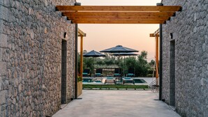 A stone building with a covered outdoor seating area and a pool. - Irissa Suites (Nafplio)