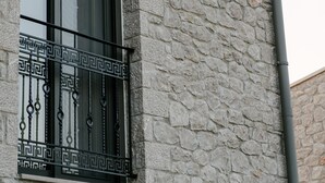 A stone building with a window featuring a decorative wrought iron balcony. - Irissa Suites (Nafplio)