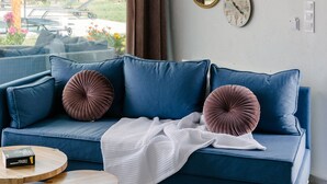 A modern living room with a blue sofa, two round mirrors, and a wall-mounted air conditioner. - Irissa Suites (Nafplio)