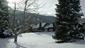 A snow-covered landscape with a house featuring a large chimney and a sloped roof. - Three Kings 37 2 Bedroom Condo (Park City)