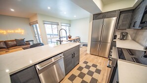 A modern kitchen with a large island, stainless steel appliances, and a checkered floor mat. - Wild Irishman 1054 (Keystone)