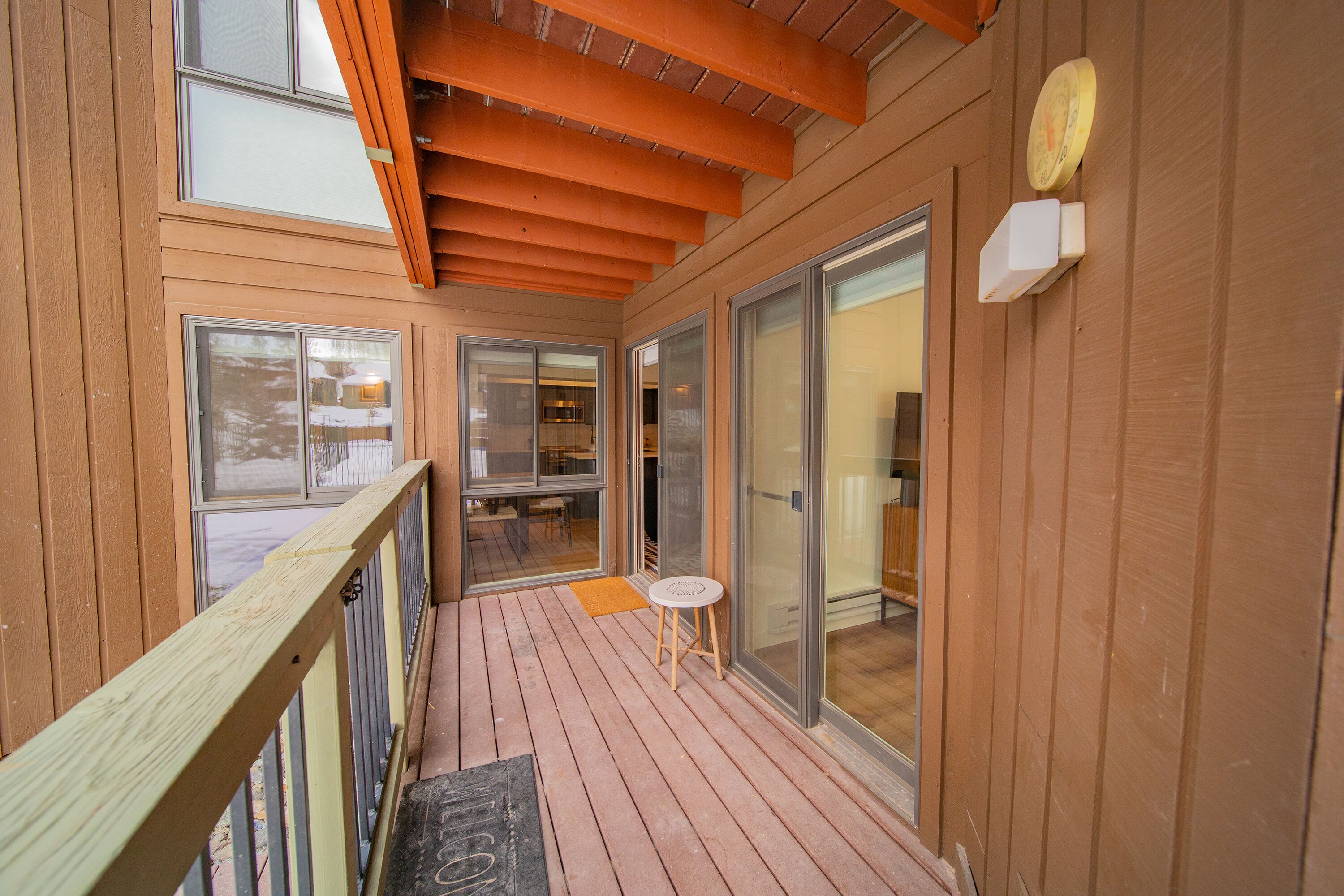 Une terrasse en bois avec une porte vitrée donnant sur un espace cuisine.