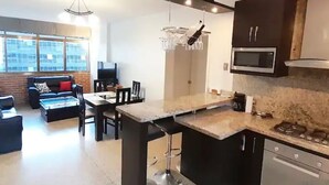 Een moderne keuken met een centraal eiland, donkere kastjes en een magnetron.