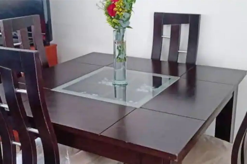 A dining table with a clear glass top, surrounded by dark wooden chairs.
