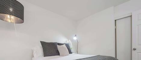 A bedroom with a bed, bedside lamp, and a door.