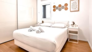 A modern bedroom with a large bed, a bedside table, and a wall-mounted shelf.