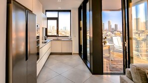 A modern kitchen with a city view, large windows, and a balcony.