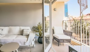 Relax in a stylish living space with a sofa, table, and potted plant, and enjoy the city view from the balcony.