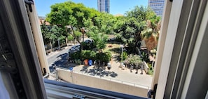 Guests can enjoy a serene view of the street lined with trees and parked cars.