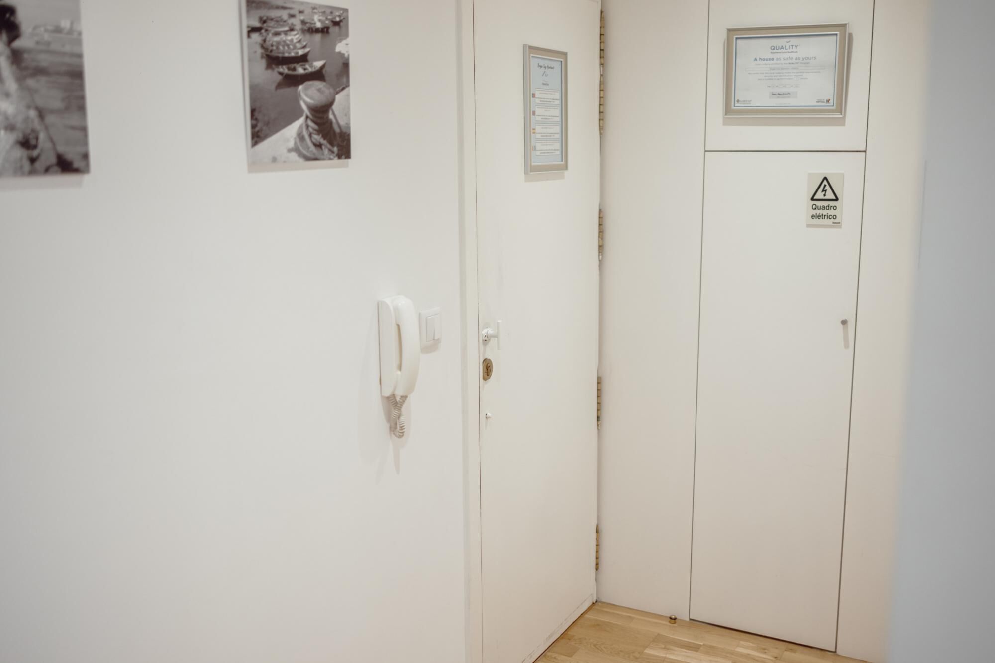 A hallway with a white door, a wall-mounted phone, and a framed certificate.