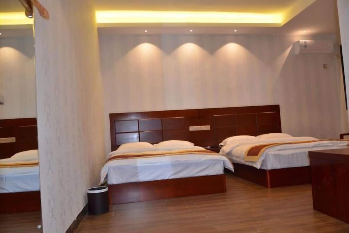 A hotel room with two beds, wooden headboards, a trash bin, and a ceiling light fixture.