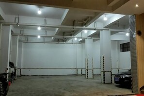 A parking garage with concrete floors, white walls, and ceiling pipes. - Yongren Hongyuan Hotel (Yongren)