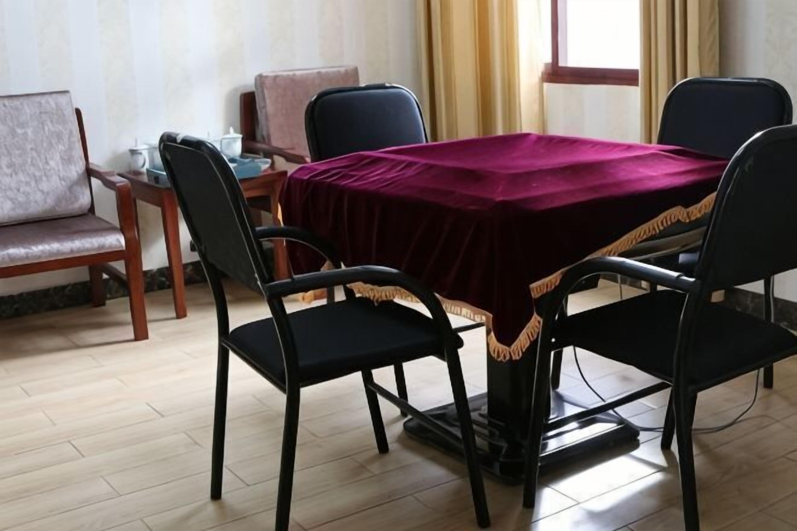 A dining area with a table covered by a red cloth, four black chairs, and a wooden bench.