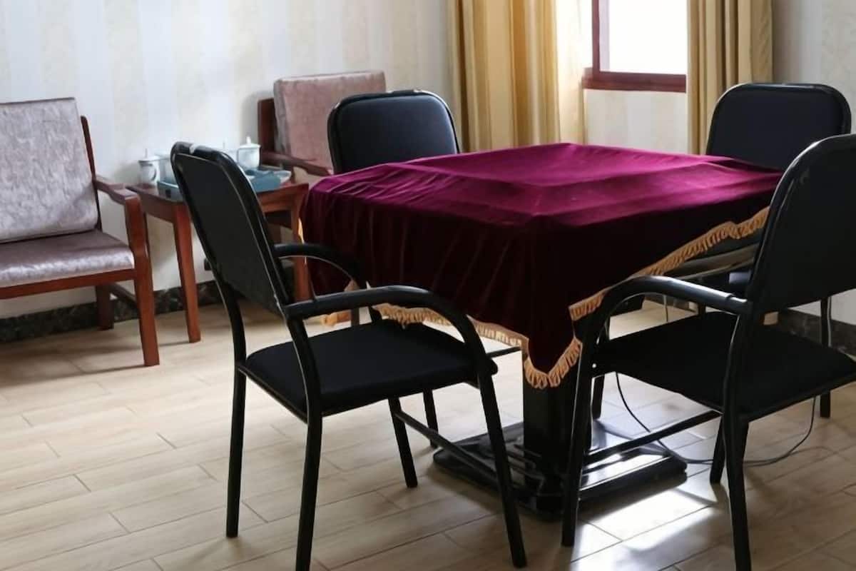 A dining area with a table covered by a red cloth, four black chairs, and a wooden bench.