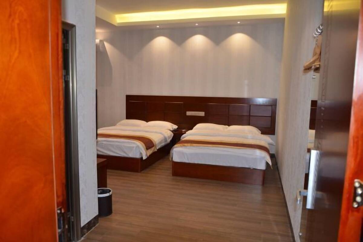 A hotel room with two beds, wooden flooring, and a modern headboard design.