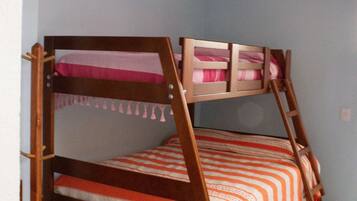 A bunk bed with a wooden frame and orange and white striped bedding.