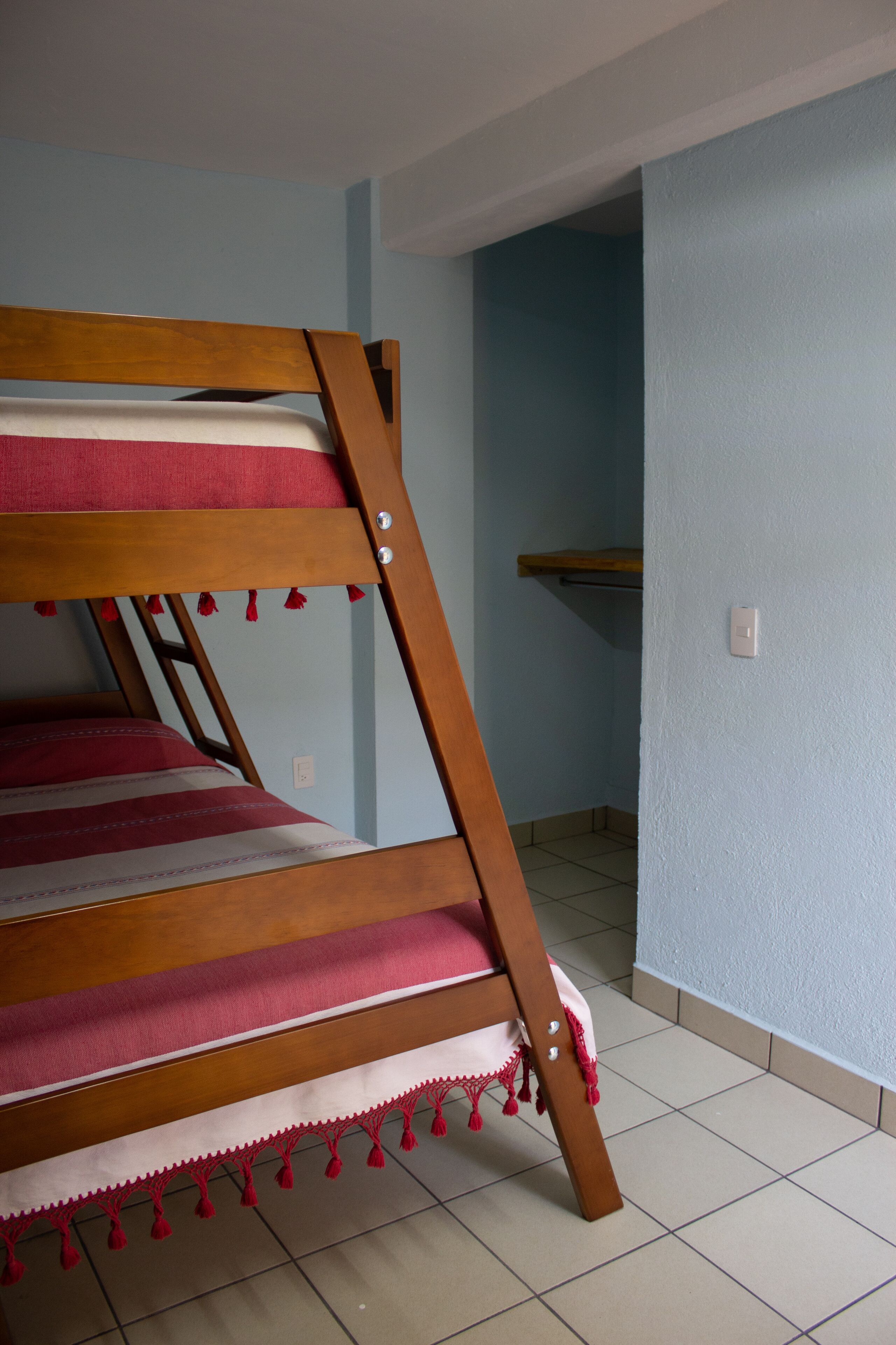 Un lit superposé avec une structure en bois et une literie rouge et blanche.
