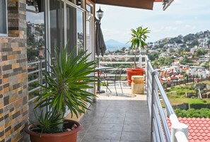 A balcony with potted plants, a view of the city, and a tiled floor. - Hotel Casa Leonor (Oaxaca)