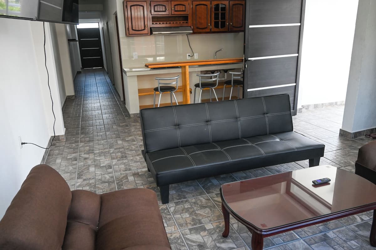 A living area with a sofa, a coffee table, and a kitchen in the background.