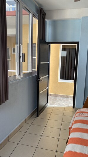 A room with a bed, a door, a window, and a view of the outside. - Hotel Casa Leonor (Oaxaca)