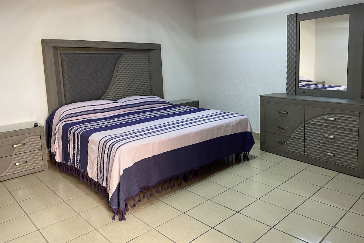 A bedroom with a bed, a dresser, and a mirror.