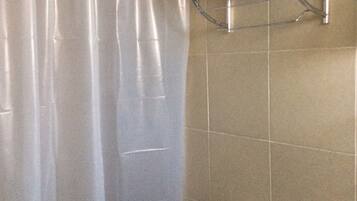 A bathroom with a shower curtain, a toilet, and a shelf with toiletries.