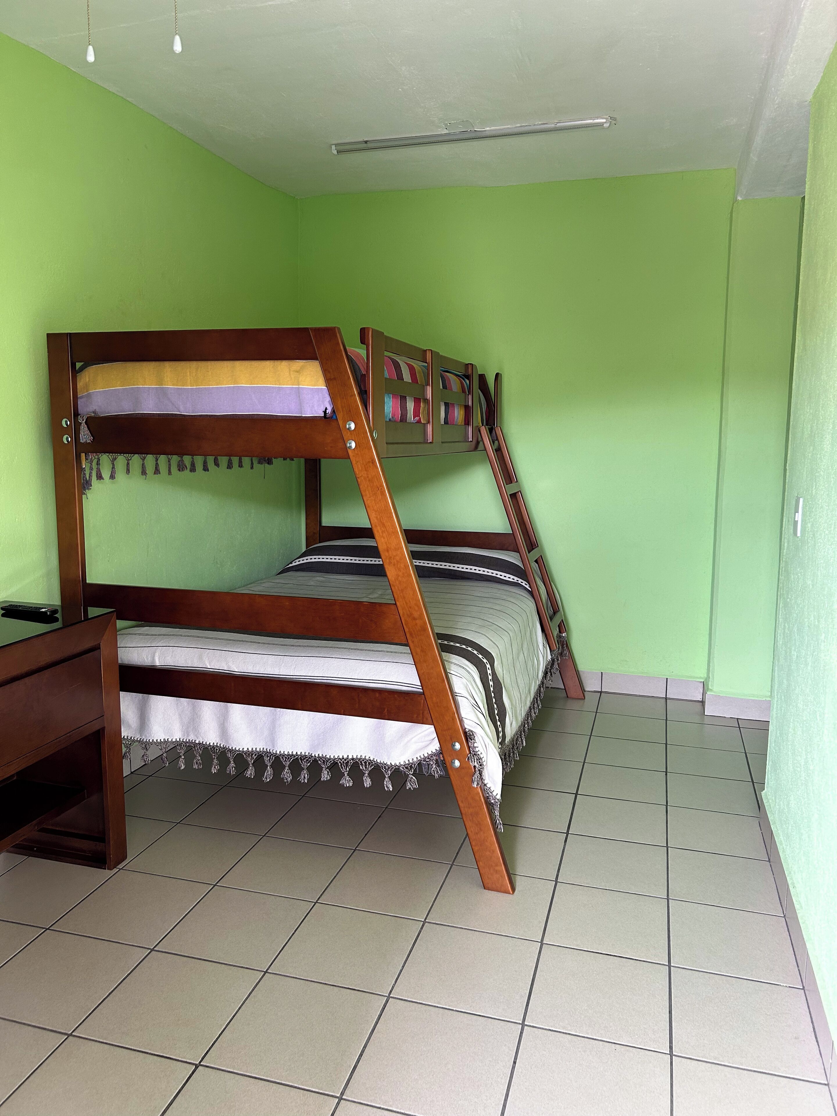 A bunk bed in a room with green walls and tiled flooring.
