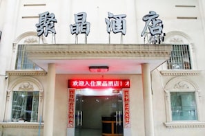 A hotel entrance with a sign above the door. - Jujin Hotel (Jiangmen)