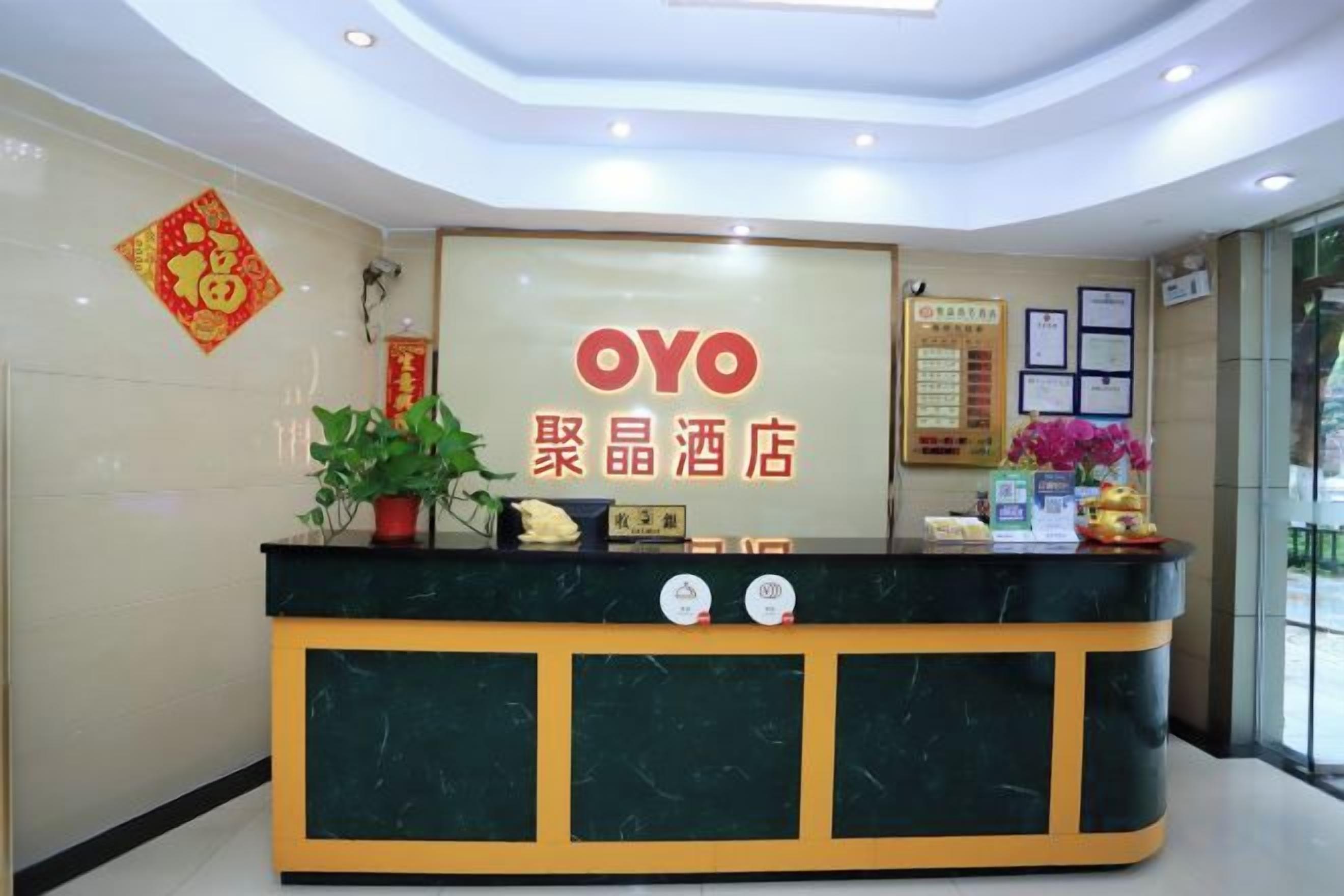 A reception desk with a sign reading 'OYO' and '聚晶酒店' indicating the hotel name.
