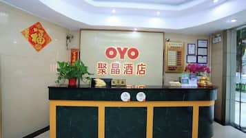 A reception desk with a sign reading 'OYO' and '聚晶酒店' indicating the hotel name.