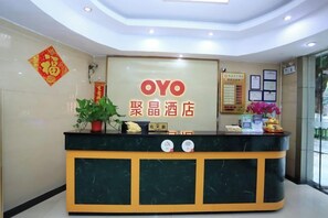 A reception desk with a sign reading 'OYO' and '聚晶酒店' indicating the hotel name. - Jujin Hotel (Jiangmen)