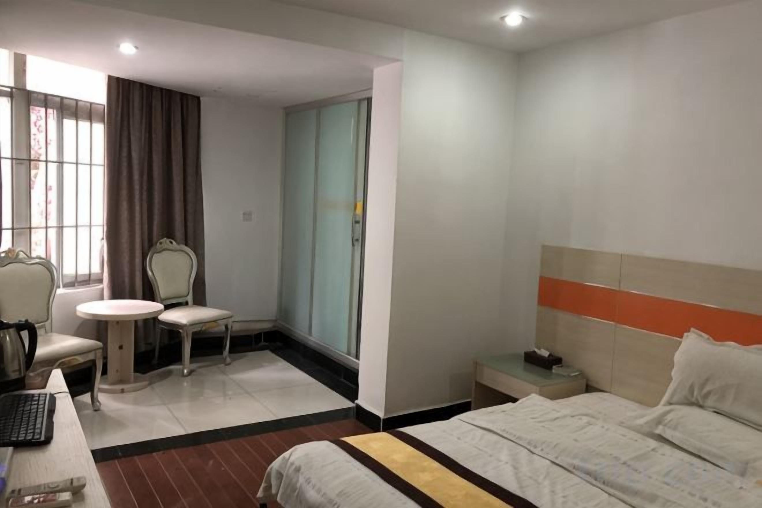 Een hotelkamer met een bed, een bureau met stoel, een klein tafeltje en een kledingkast.
