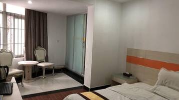 Een hotelkamer met een bed, een bureau met stoel, een klein tafeltje en een kledingkast.