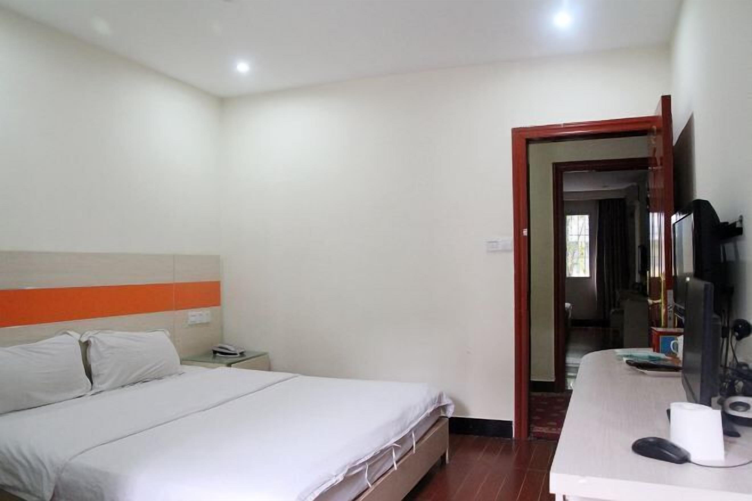 A hotel room with a bed, a desk with a computer, and a mirror.