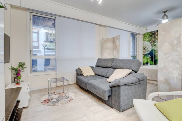 Relax in this stylish living room with a sofa, side table, and potted plant, offering a view of the outside and a balcony.