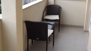 Ein kleiner Balkon mit zwei Korbstühlen und einem Glastisch.