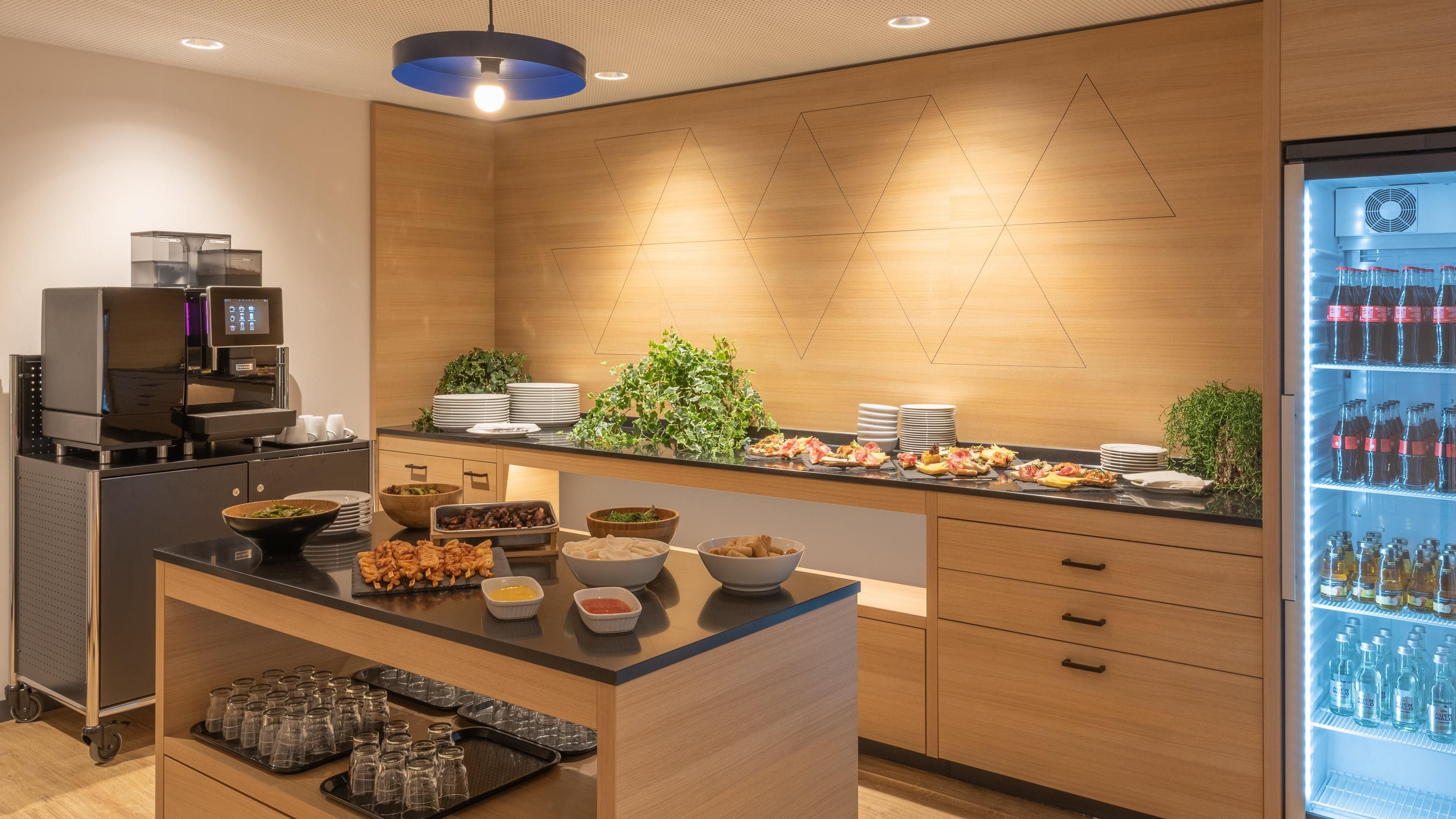 Una cocina moderna con una isla central, una cafetera y un refrigerador lleno de bebidas.