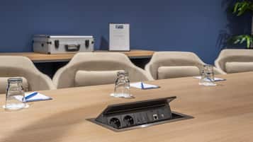 Een vergaderruimte met een lange tafel, meerdere stoelen, een projecter en een waterfles op elke stoel.