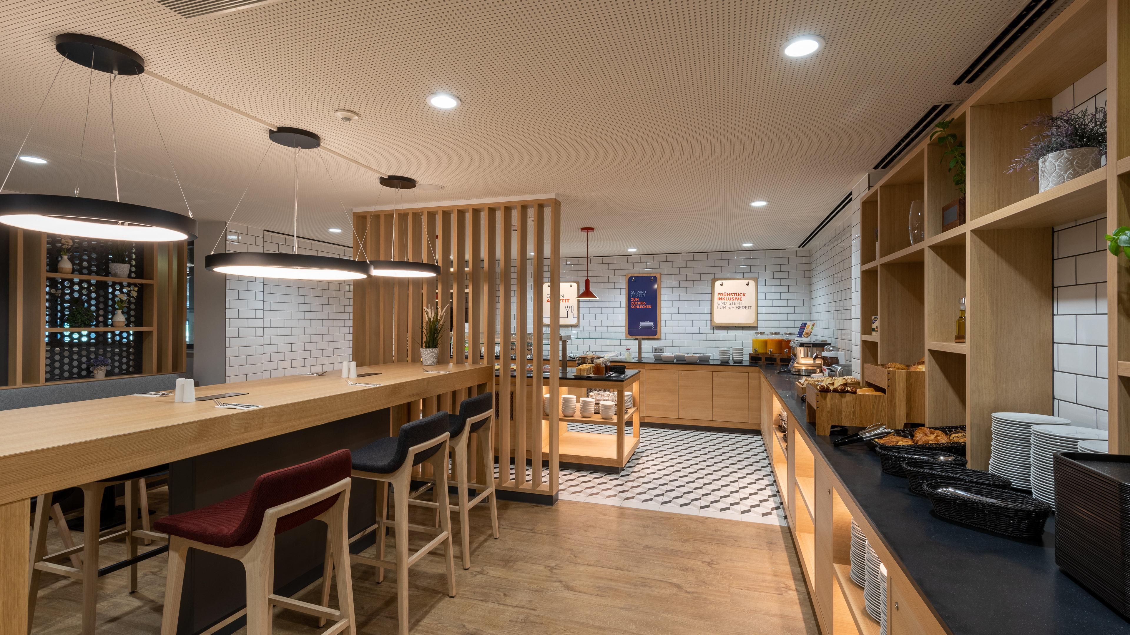 A modern kitchen with a bar area, wooden furniture, and a tiled backsplash.