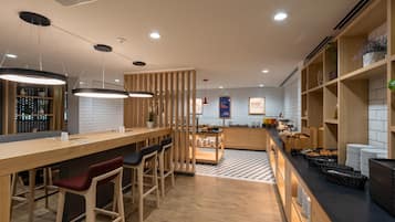 A modern kitchen with a bar area, wooden furniture, and a tiled backsplash.