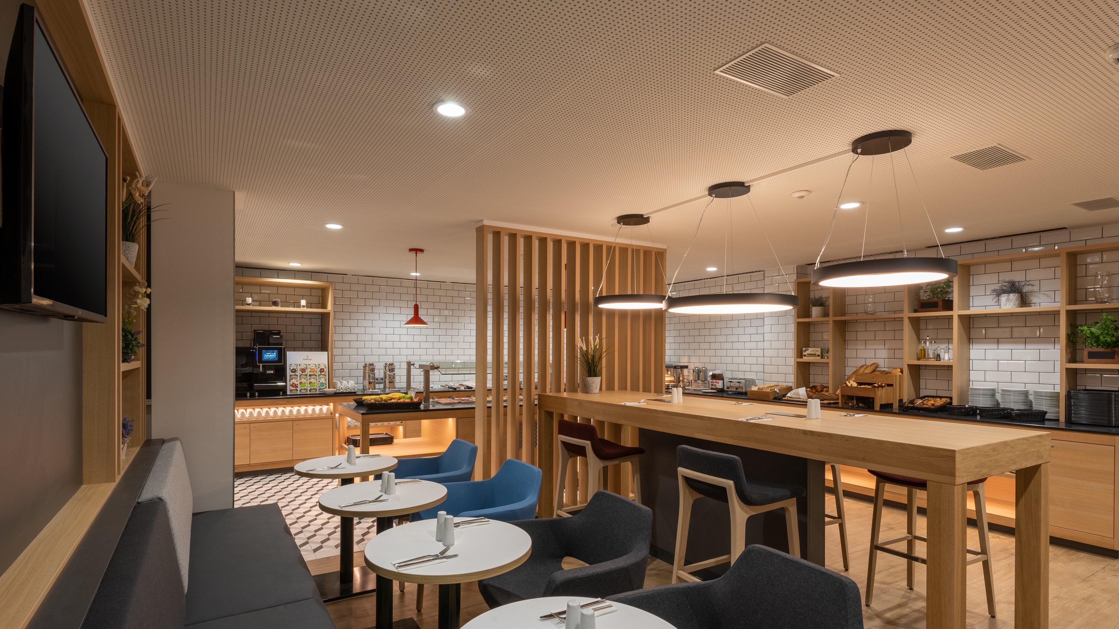 A modern restaurant with a bar area, round tables, and blue chairs.