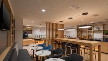 A modern restaurant with a bar area, round tables, and blue chairs.
