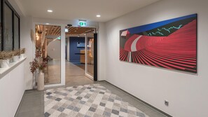 A modern hallway with a checkered rug, a reception desk, and a large abstract painting. - Holiday Inn Express Hamburg South A7 As42 (Egestorf)