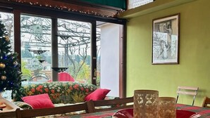 Un coin repas avec une nappe à carreaux, un sapin de Noël et une vue sur l’extérieur.