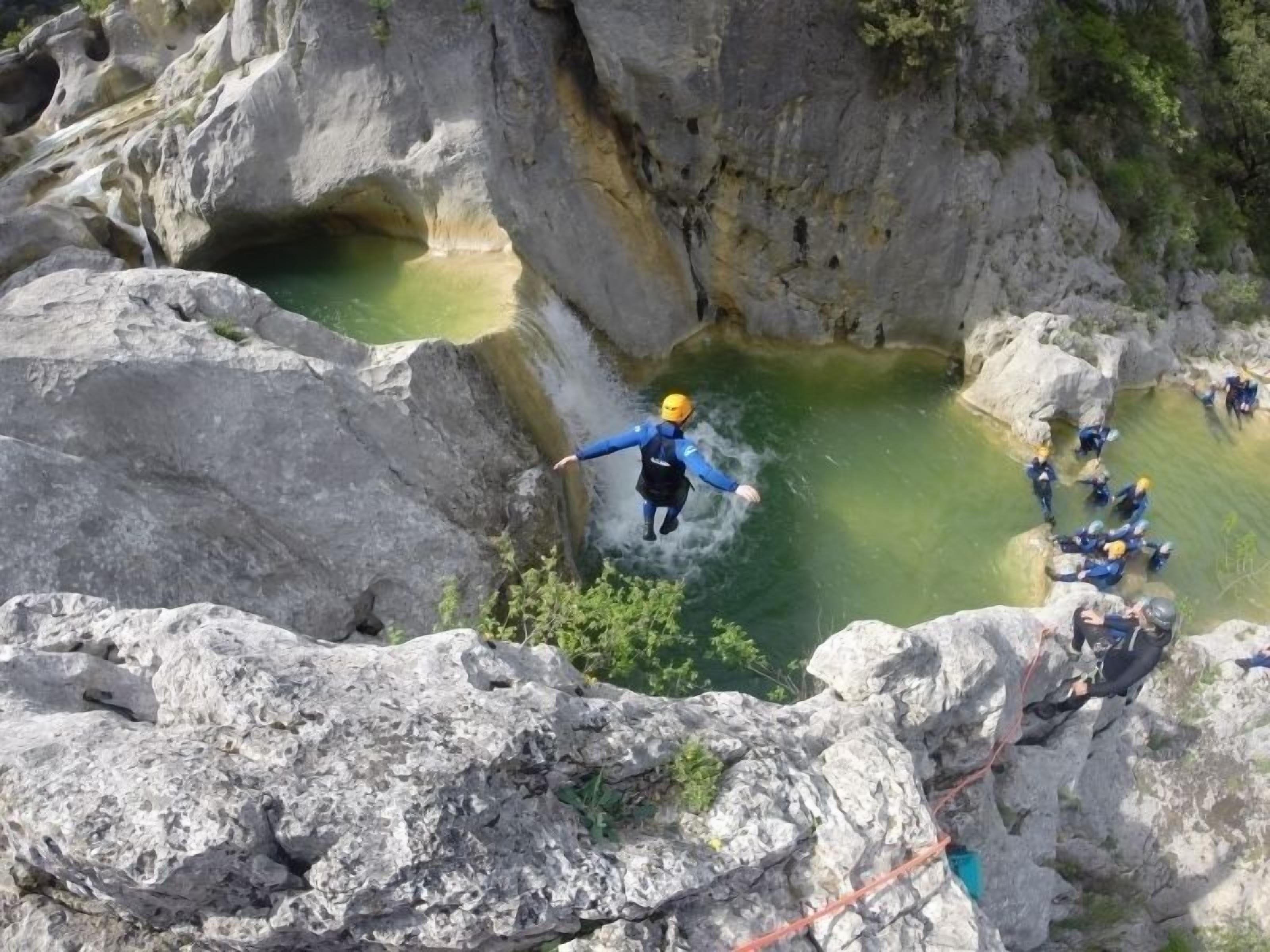 A bungee jumping activity with participants and a guide, set against a rocky cliff backdrop.