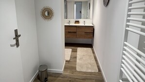 A narrow hallway with wooden flooring, a white door on the left, a trash bin, and a radiator on the right. - VILLA 14 Pers. Private pool, pétanque, terrace. 1km from Vallon center (Vallon-Pont-d'Arc)