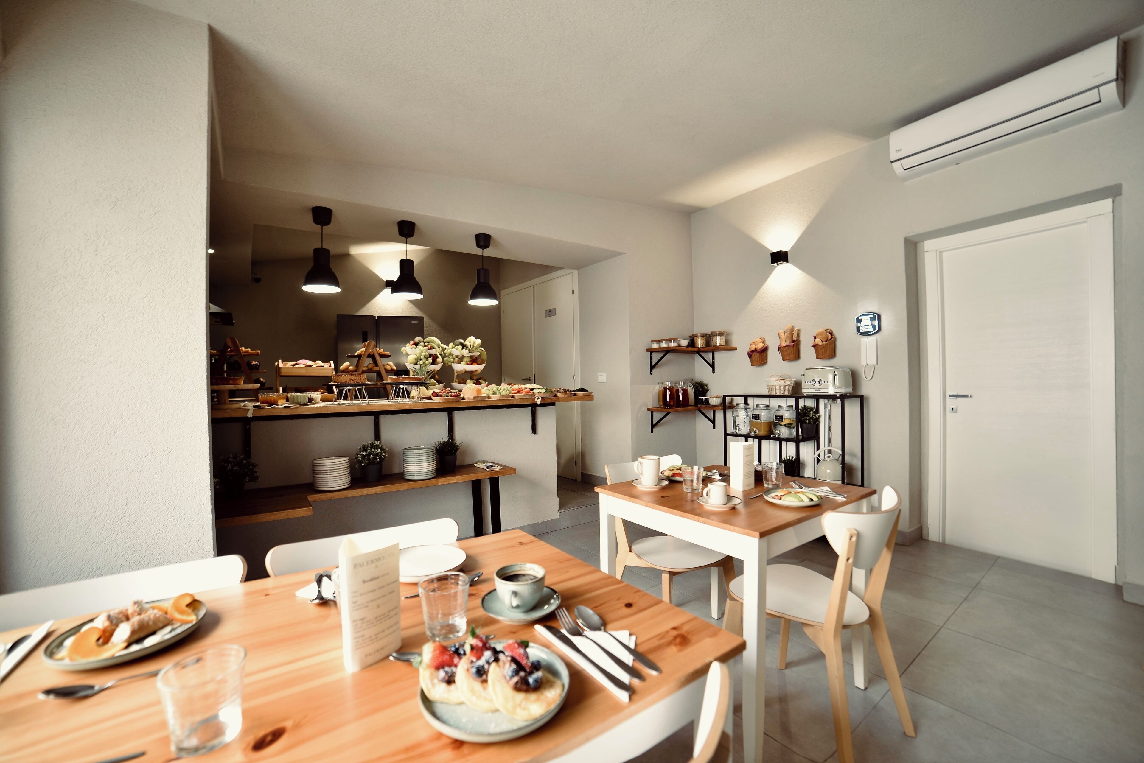 Una cocina moderna con encimeras de madera, un comedor con mesa y sillas de madera, y una isla visible con diversos objetos.